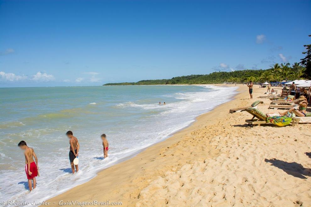 Imagem de meninos molhando os pés nas águas da Praia do Rio Verde.